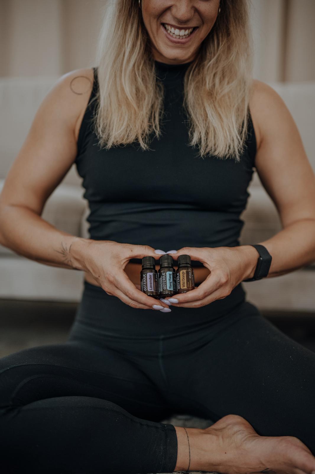Anki lacht und hält drei dōTERRA-Fläschchen in den Händen